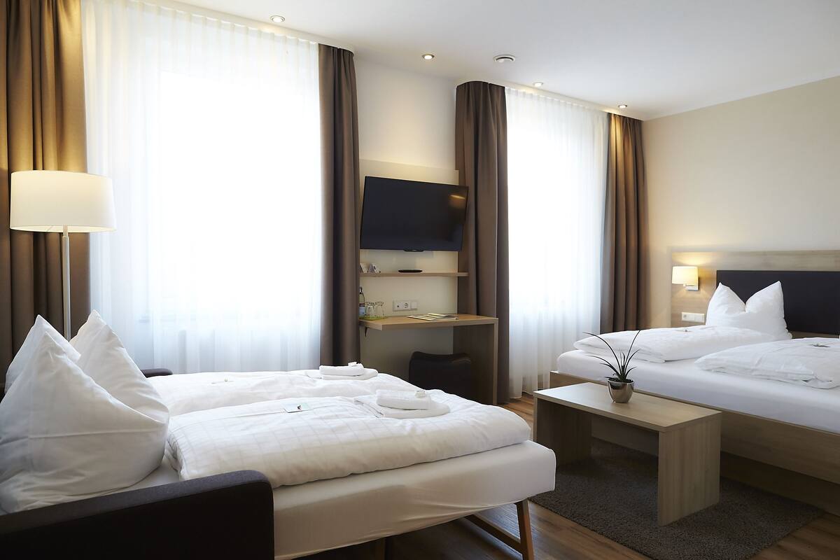 Une chambre d’hôtel avec deux lits, un bureau, une télévision et une lampe.