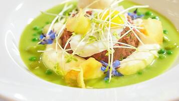 Un plato blanco con salsa verde, una esfera blanca y guarniciones.