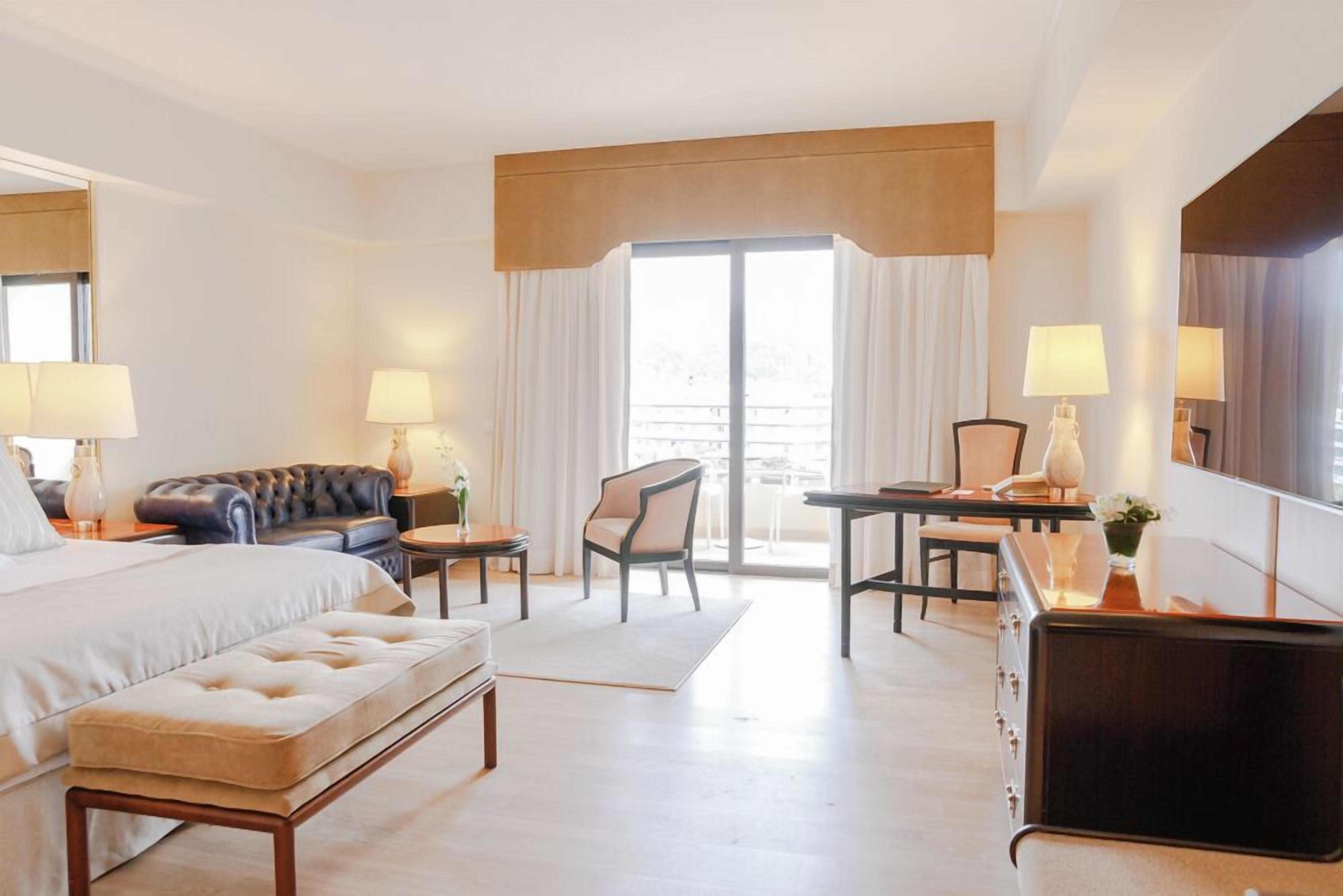 A hotel room with a bed, a sofa, a desk, a chair, and a dresser.