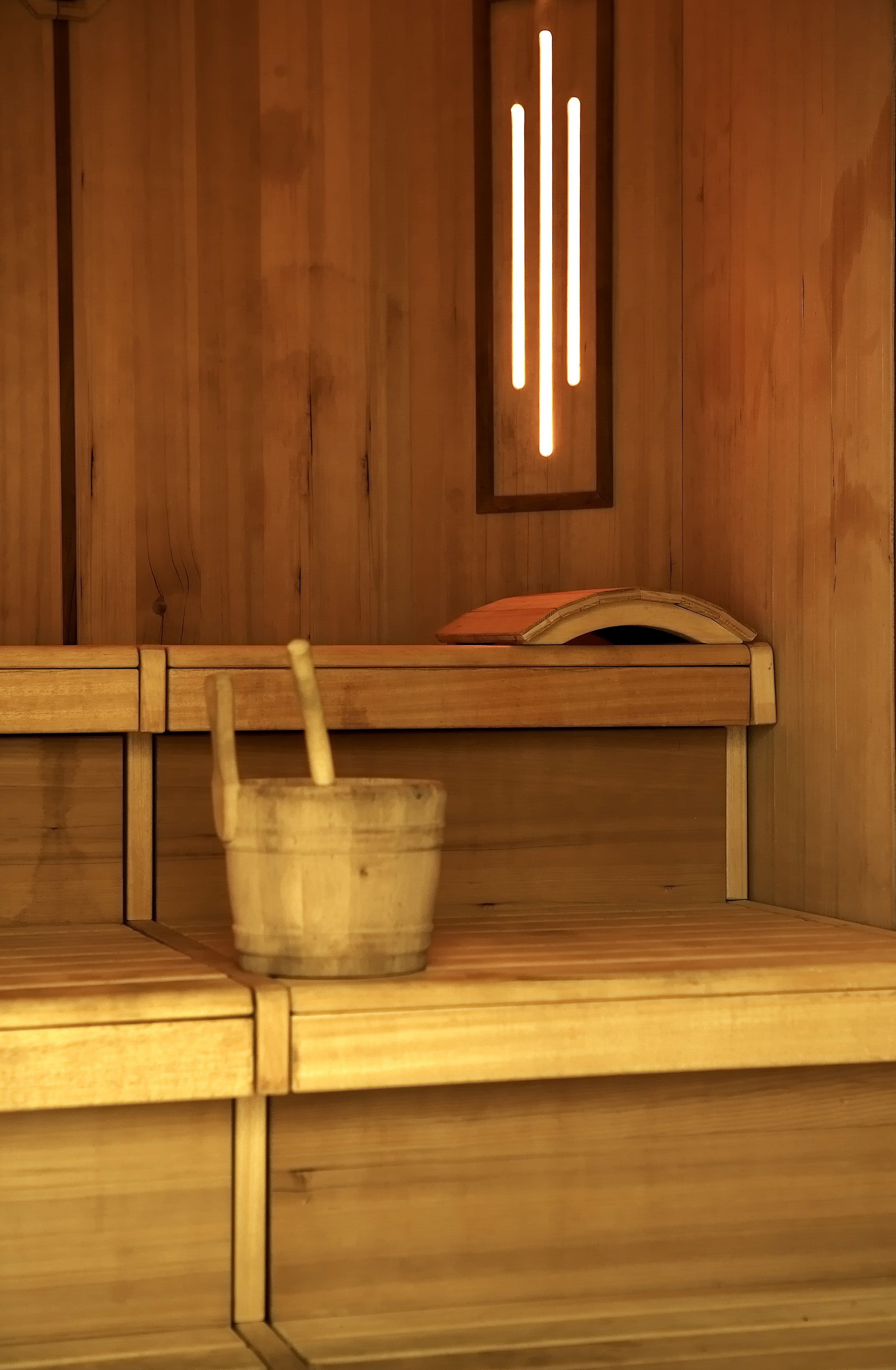 A wooden sauna bench with a bucket and a wooden spoon.