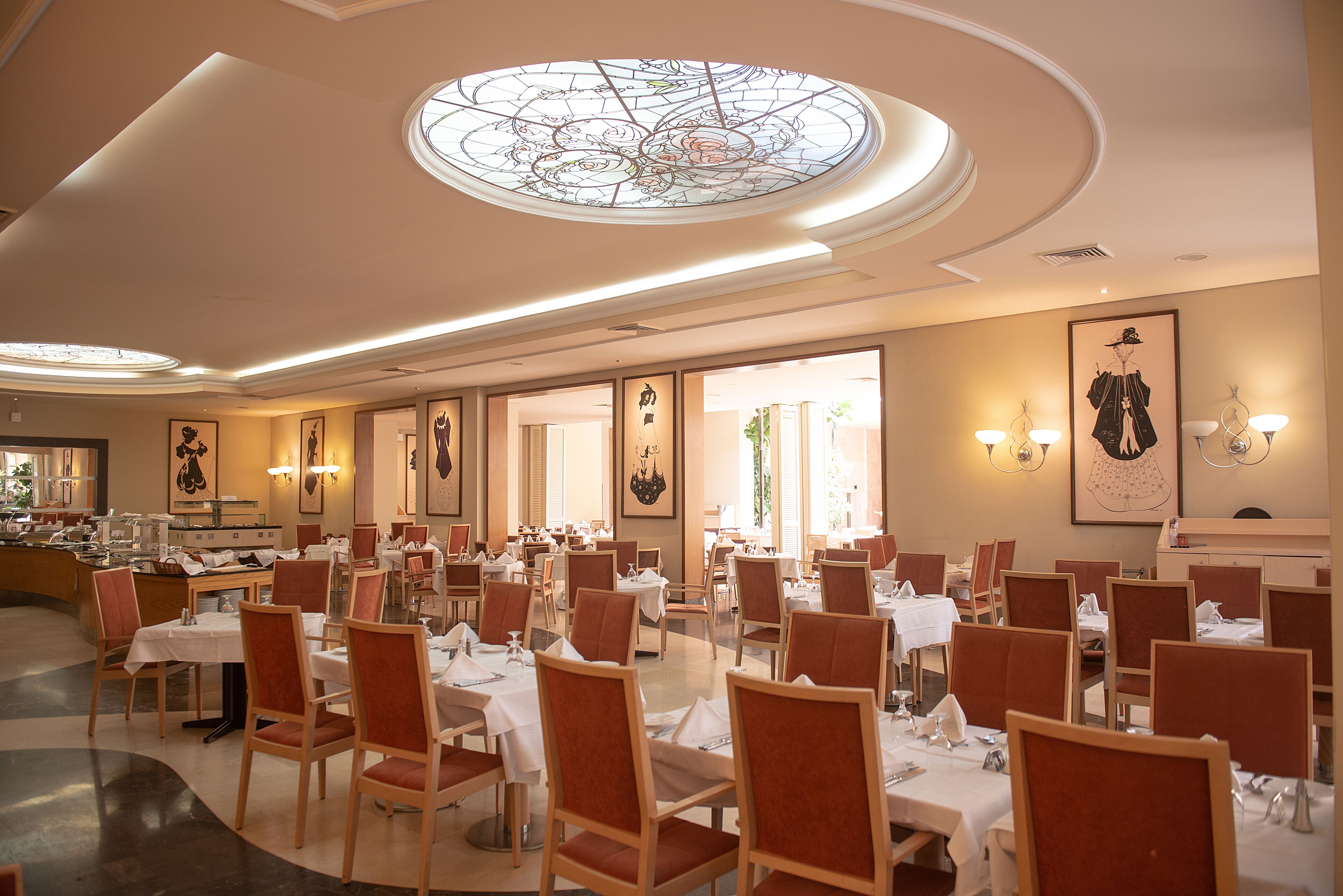 A spacious dining area with multiple tables and chairs, large windows, and decorative wall art.
