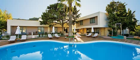 Ein Pool mit Liegestühlen und Sonnenschirmen, umgeben von modernen Gebäuden und Bäumen.