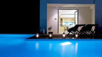 Un área de piscina con sillones de descanso y velas, que da paso a una cocina bien iluminada.