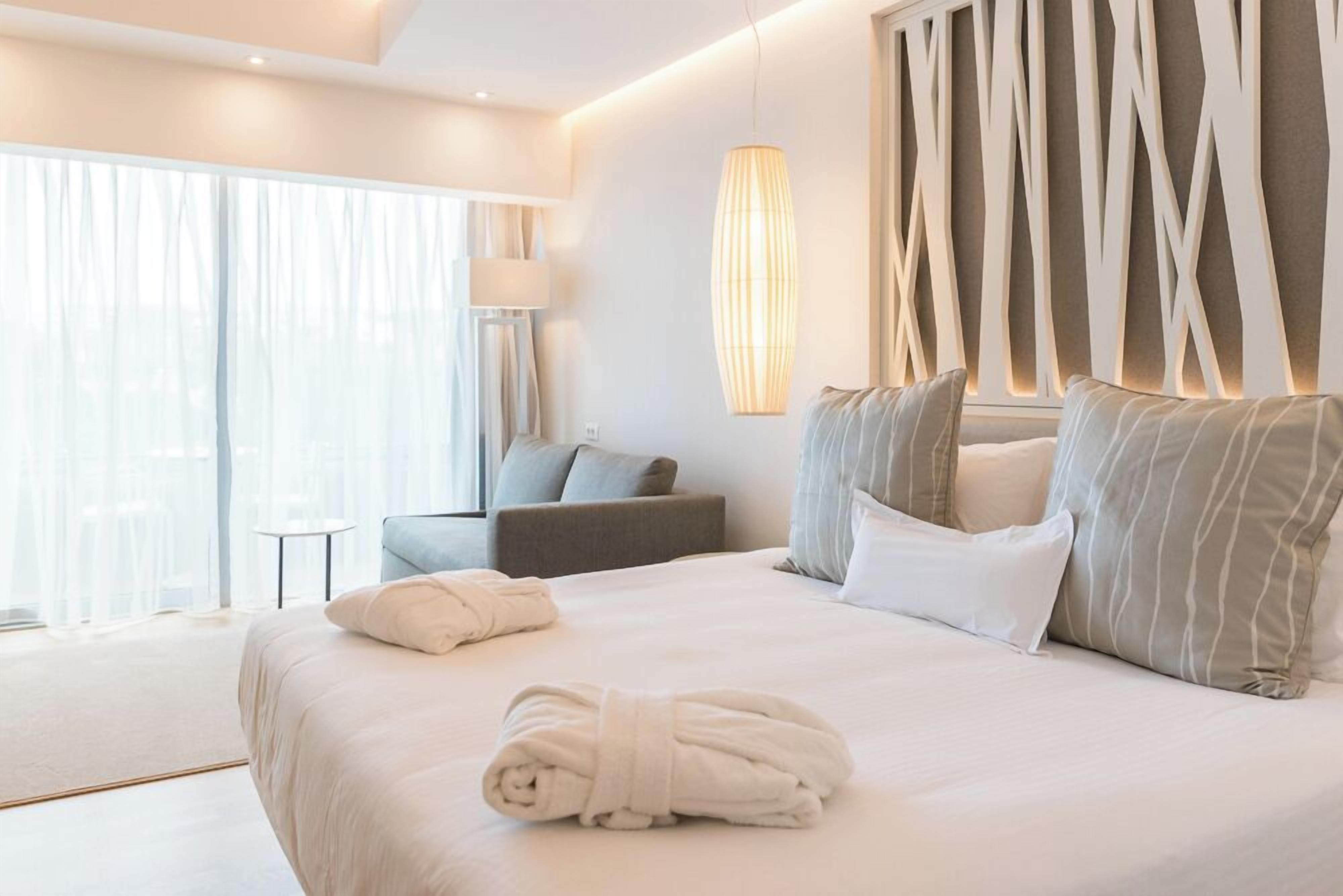 Una habitación de hotel moderna con una cama grande, un rincón de descanso y vistas al exterior.