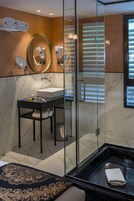 Ein modernes Badezimmer mit einer Duschkabine aus Glas, einem Marmorwaschtisch und einem großen Spiegel.