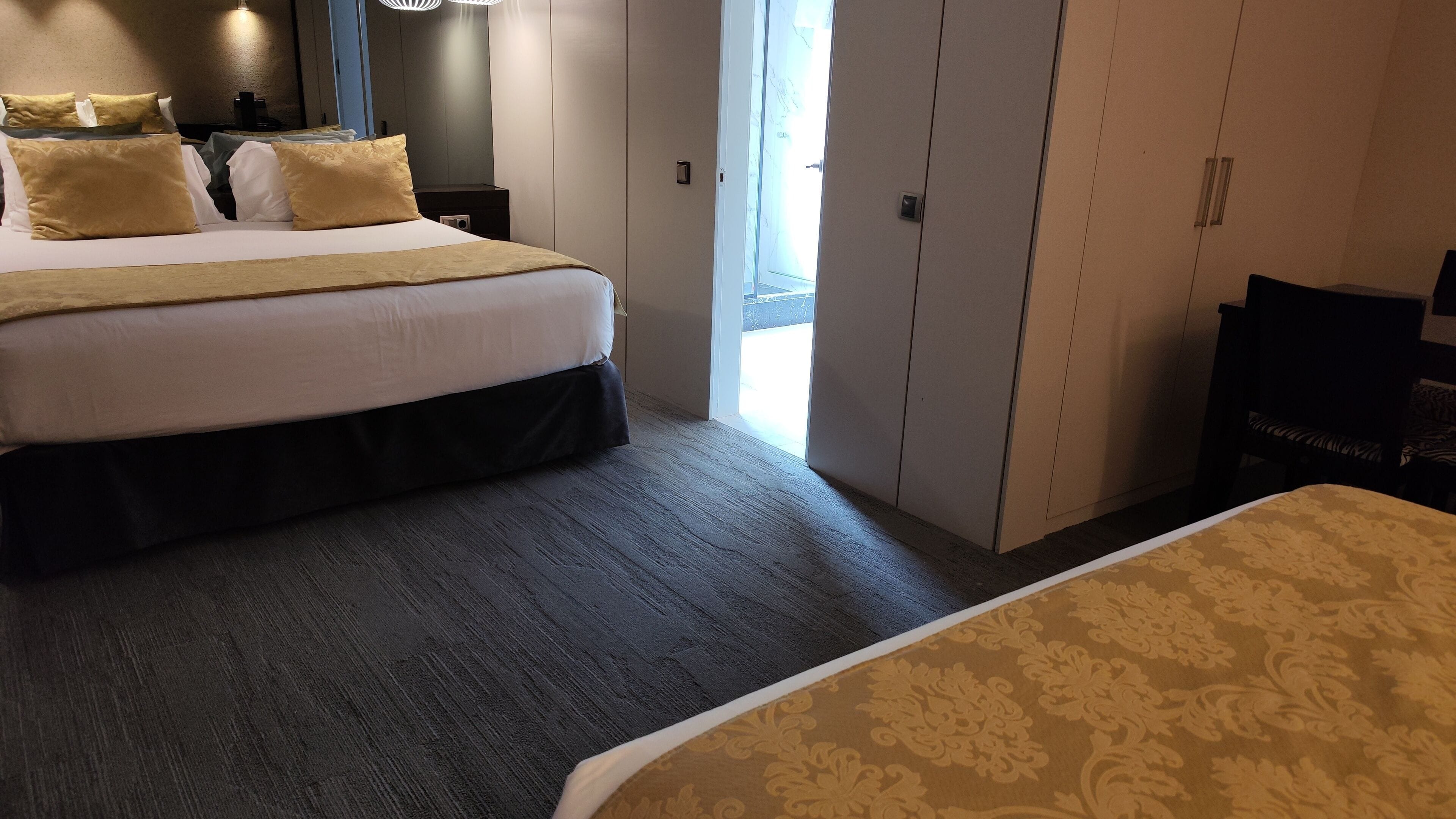 Quarto de hotel com uma cama grande, um guarda-roupa e uma escrivaninha.