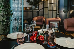 A dining table set with wine glasses, plates, and roses.