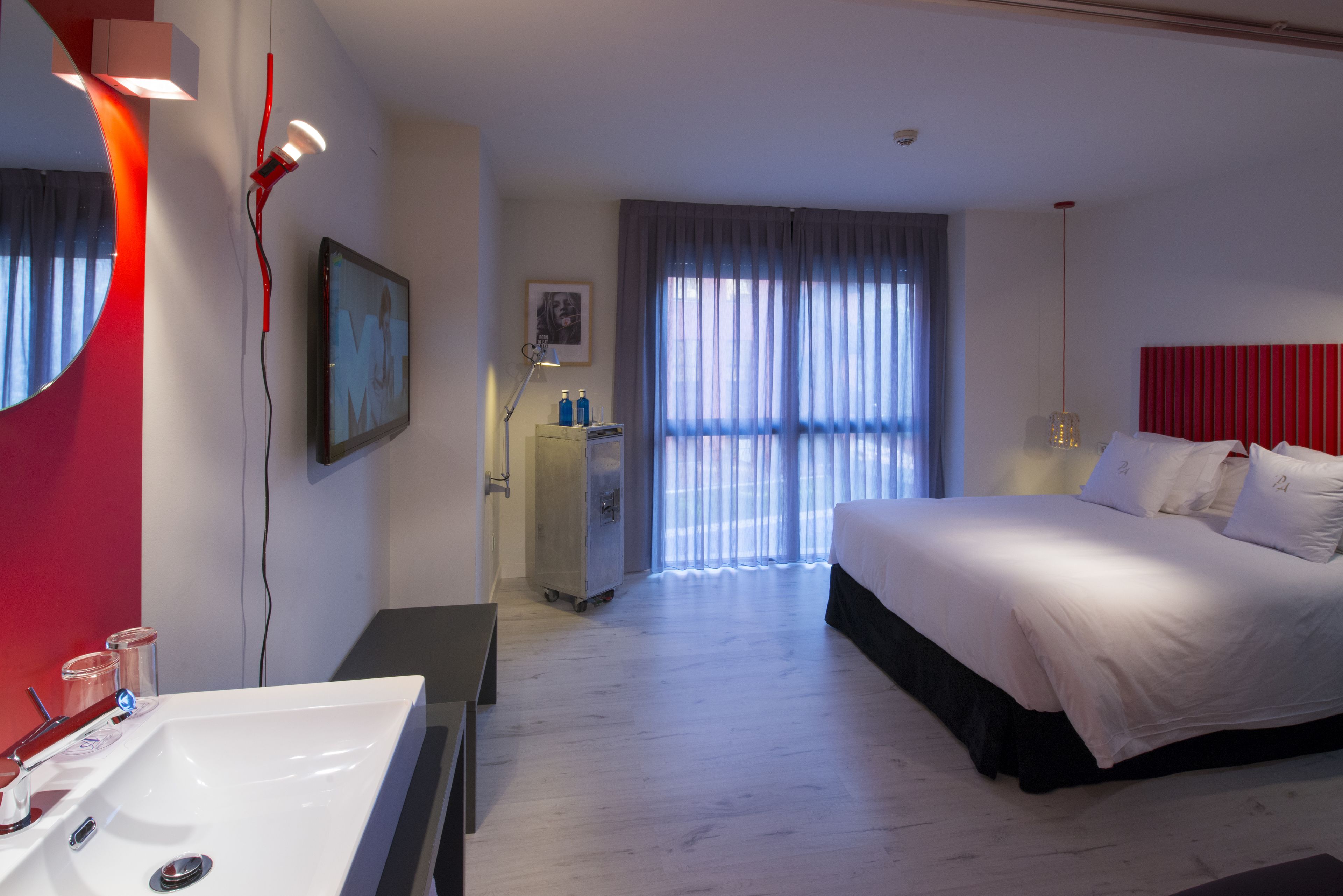 Een moderne hotelkamer met een groot bed, een witte wastafel en een spiegel.