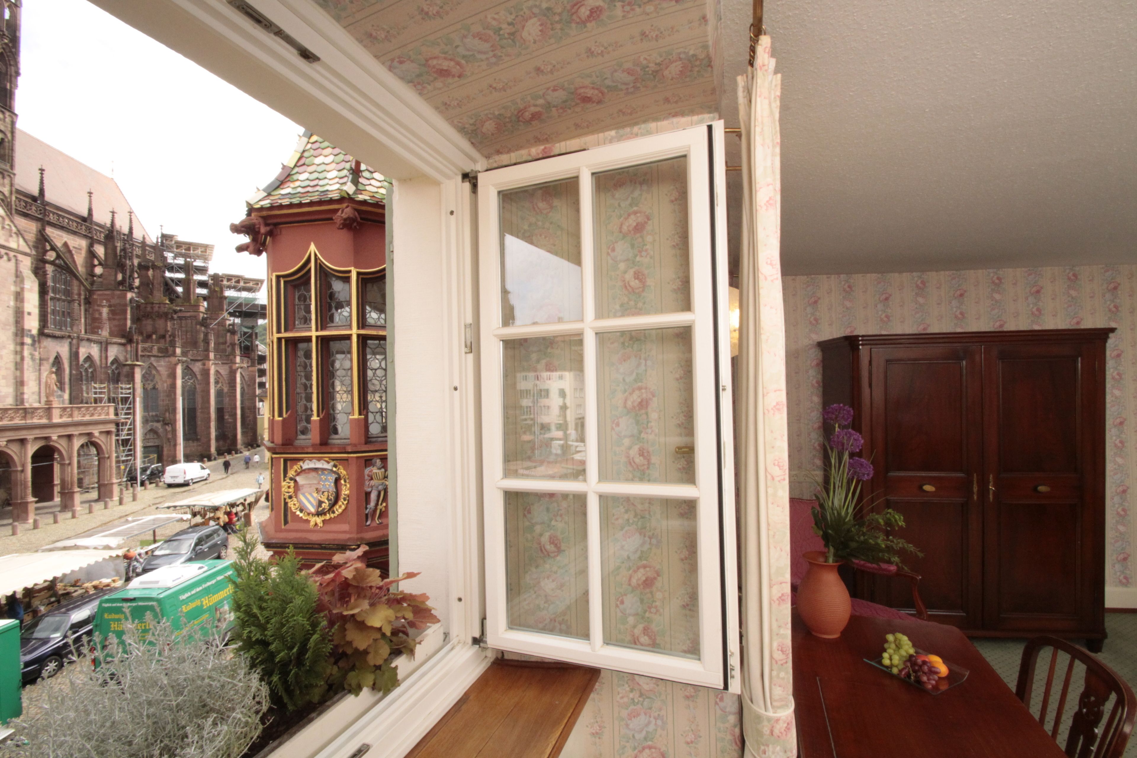 A room with a view of a historic building, a clock tower, and a dining area with a table and chairs.