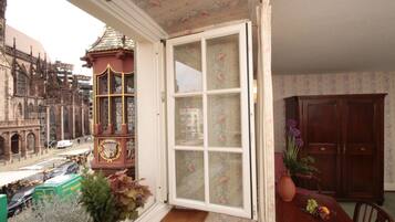 A room with a view of a historic building, a clock tower, and a dining area with a table and chairs.