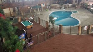 Un espace piscine intérieur doté d’une terrasse en bois, d’une table de billard et d’un petit bassin.