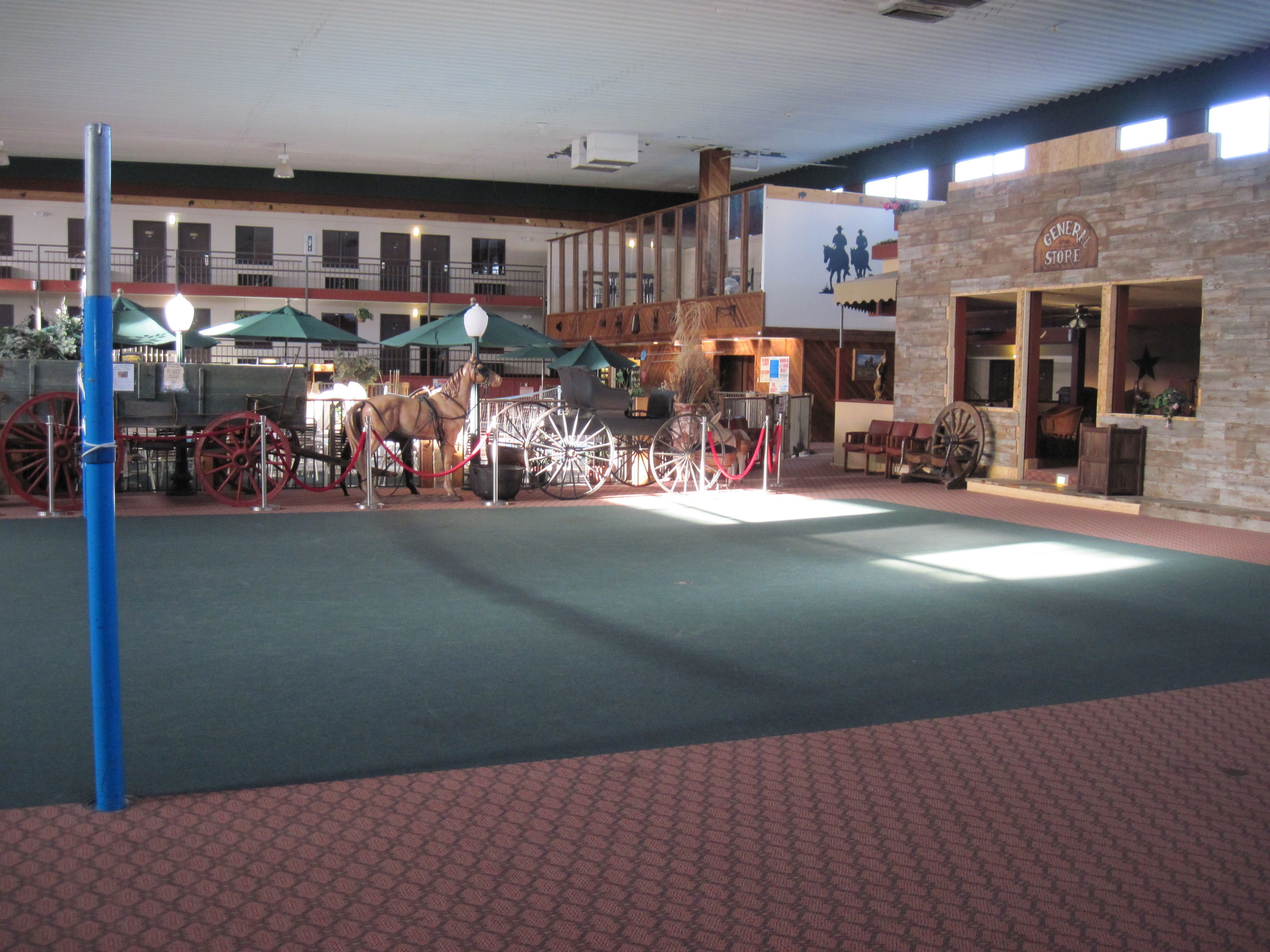 An indoor space with a horse and carriage display, a General Store sign, and a brick building facade.