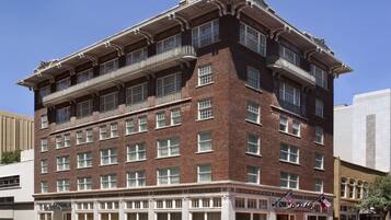 A multi-story brick building with a classic architectural style, featuring balconies and large windows.