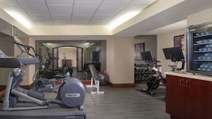 Un gimnasio con cintas de correr, elípticas y pelotas de ejercicio.