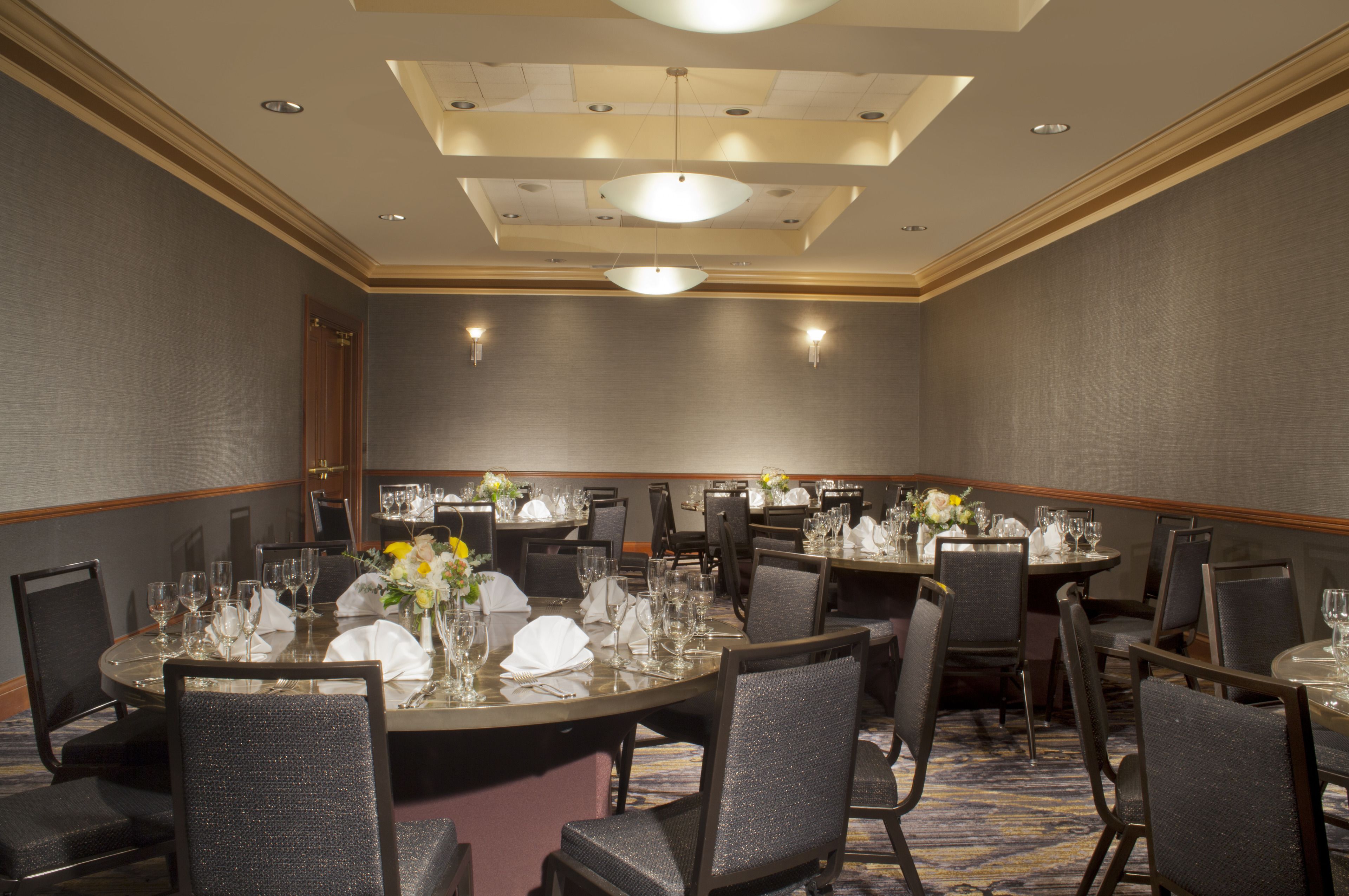 A conference room with round tables, chairs, and a chandelier.