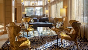 Un vestíbulo espacioso con una amplia zona de estar, un candelabro y ventanas grandes con cortinas.
