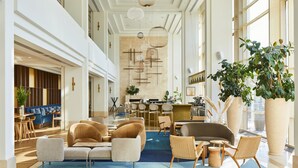 A spacious lobby with a modern design, featuring a mix of seating areas, a bar, and large windows allowing natural light. - Copenhagen Marriott Hotel (Copenhagen)
