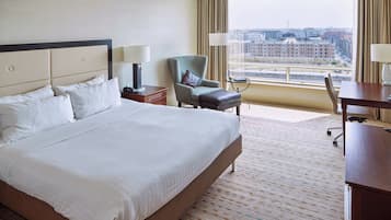 Een hotelkamer met een groot bed, een bureau, een stoel en uitzicht op de stad.