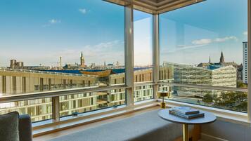A modern room with large windows offering a city view, a small round table, and a comfortable seating area.