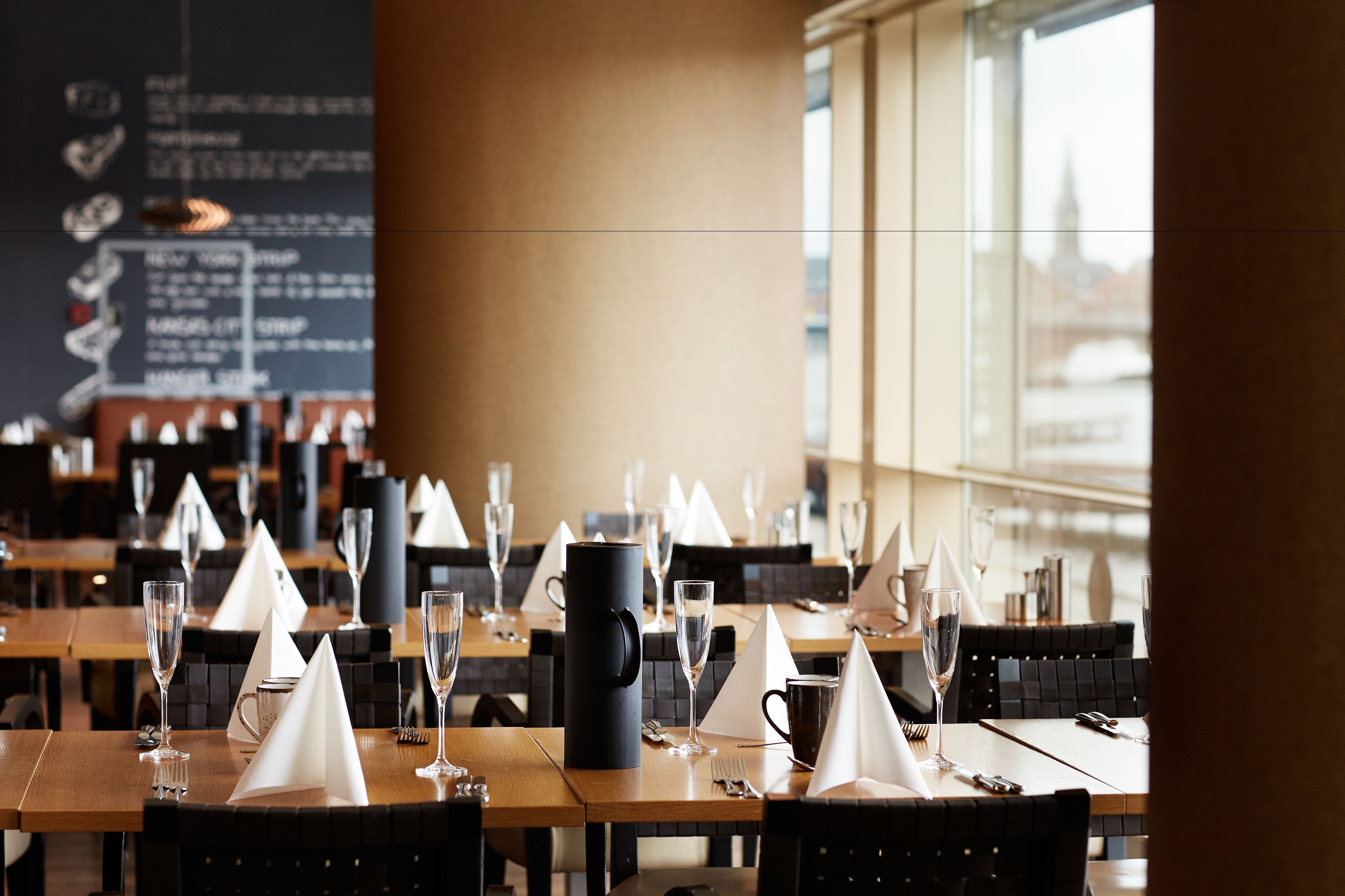 Un restaurante con mesas dispuestas para comer, incluyendo copas de vino y servilletas.