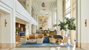 A spacious lobby with a blue carpet, leather sofas, and a large potted plant. - Copenhagen Marriott Hotel (Copenhagen)
