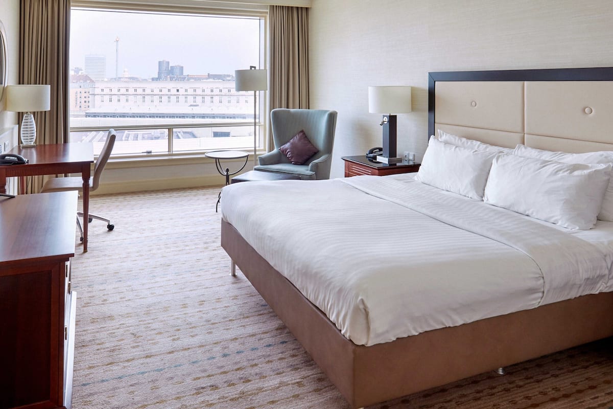 Habitación de hotel con una cama grande, un escritorio, una silla y vistas a la ciudad.