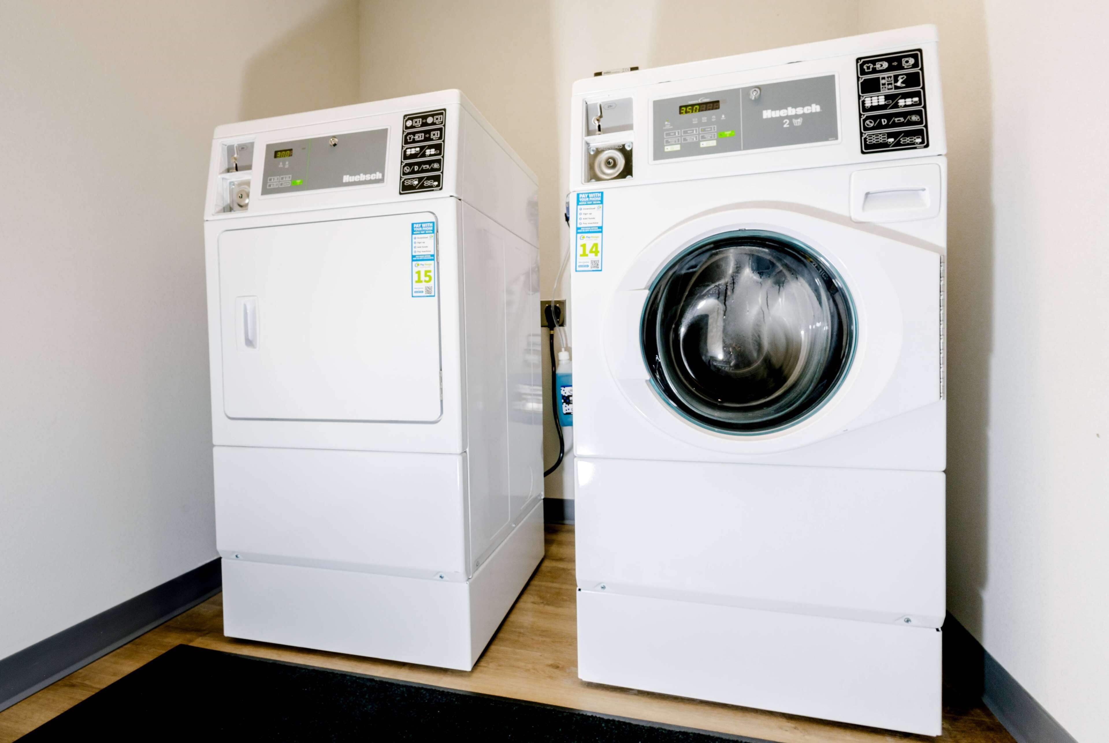 Two white front-loading washing machines in a laundry room.