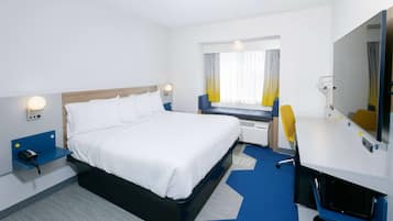 Ein Hotelzimmer mit Bett, Nachttisch, Schreibtisch, Stuhl und einem großen Spiegel.