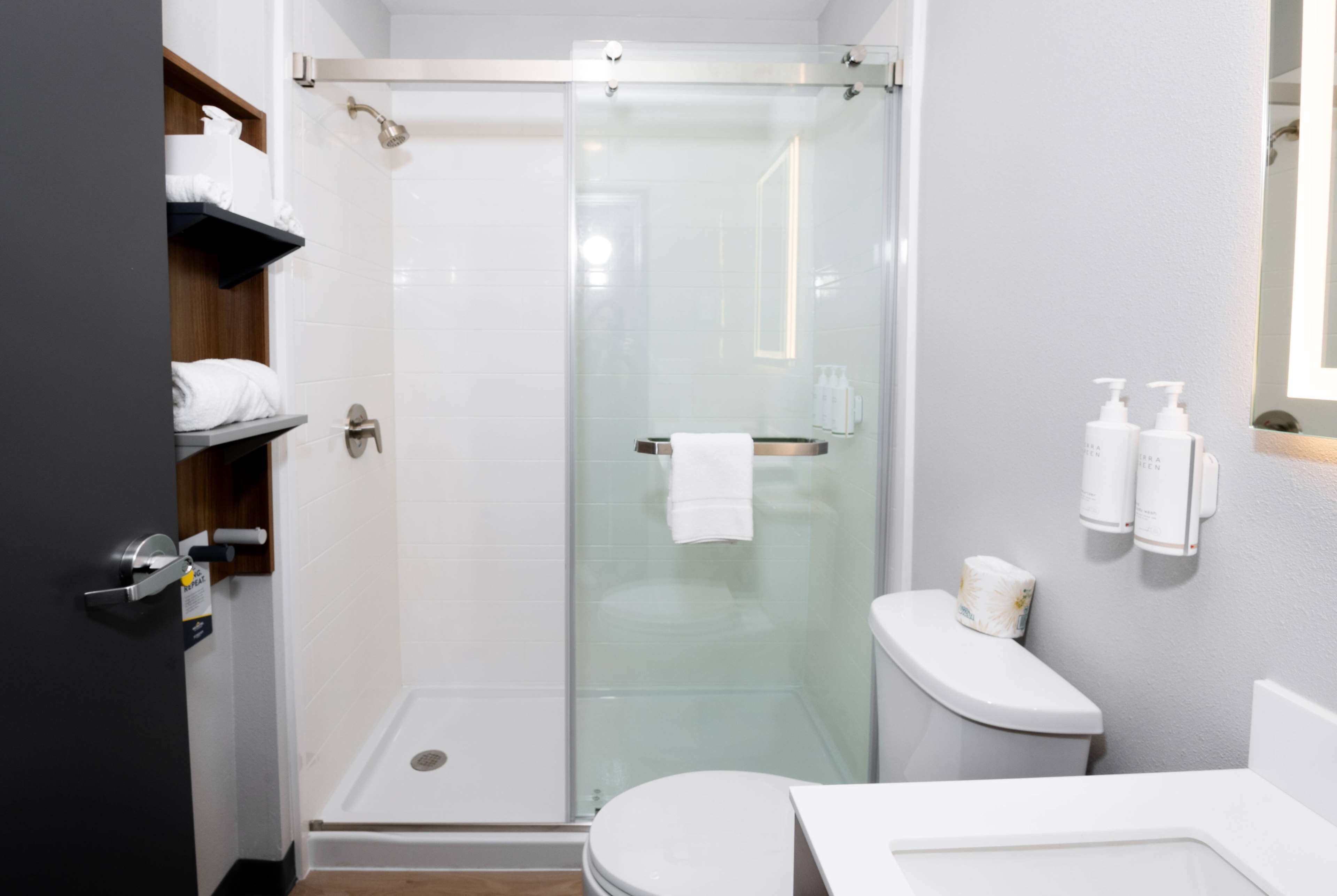 A modern bathroom with a glass-enclosed shower, a toilet, and a sink.
