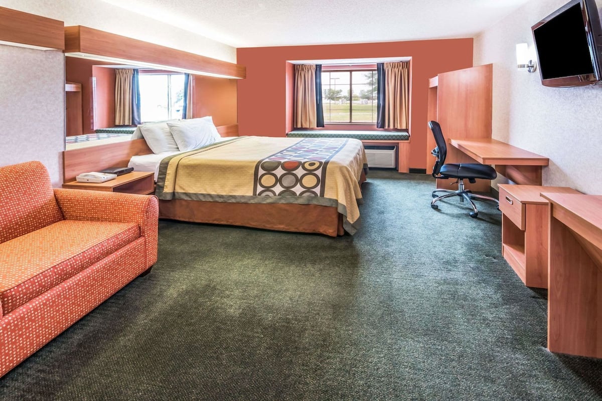 Una camera d'albergo con un letto, una scrivania, una sedia e una televisione.