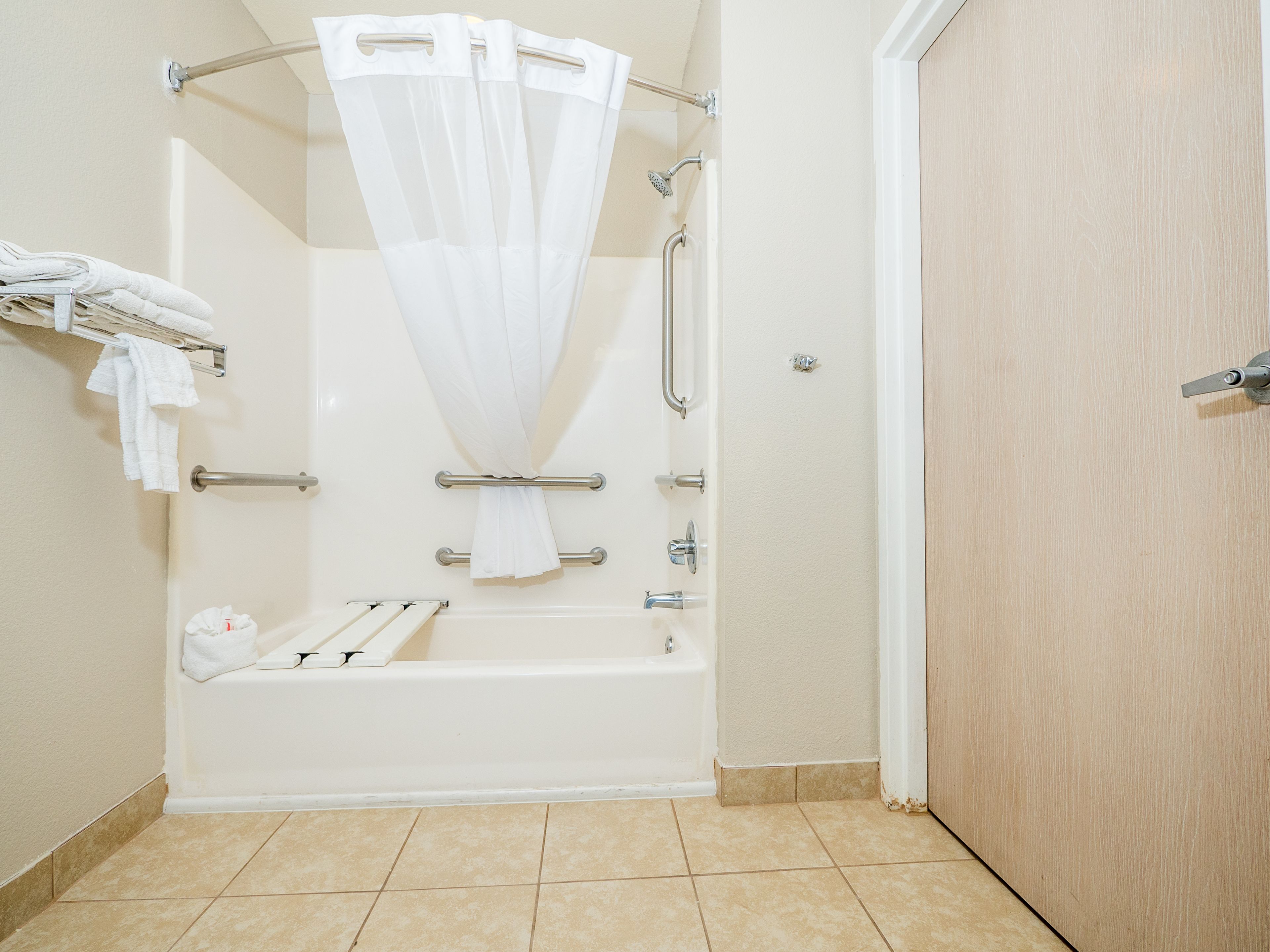 A bathroom with a bathtub, a shower curtain, a towel rack, and a door.