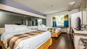 Habitació d'hotel amb dos llits, un escriptori amb un ordinador i una finestra amb cortines.
