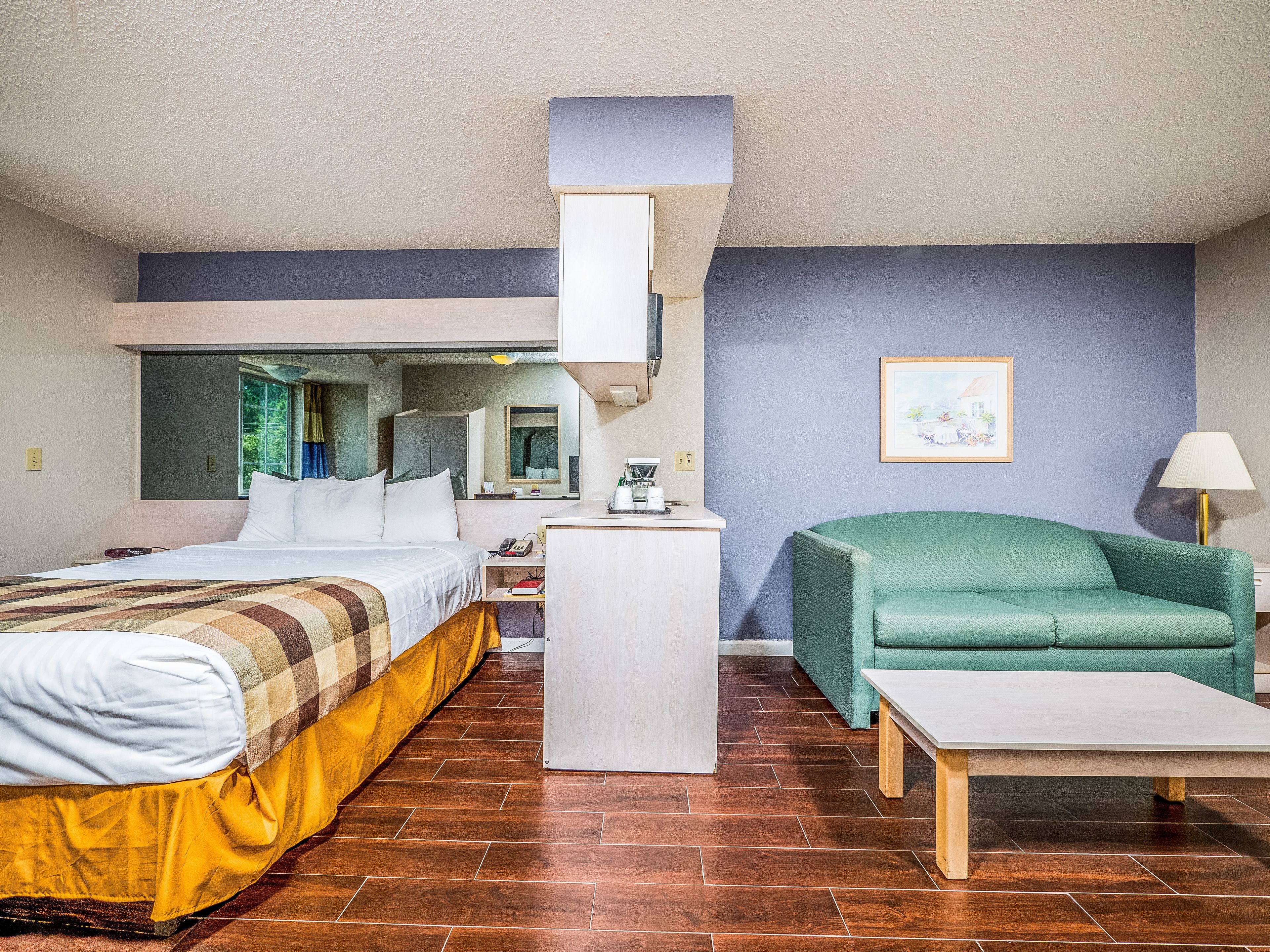 Una habitación de hotel con una cama, un escritorio, un sofá verde y una mesita.
