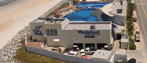 Un resort con una piscina grande, vista al mar y un letrero con temática de delfines.