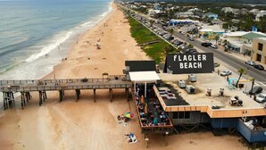 Una playa con un muelle y un edificio que dice "FLAGLER BEACH".