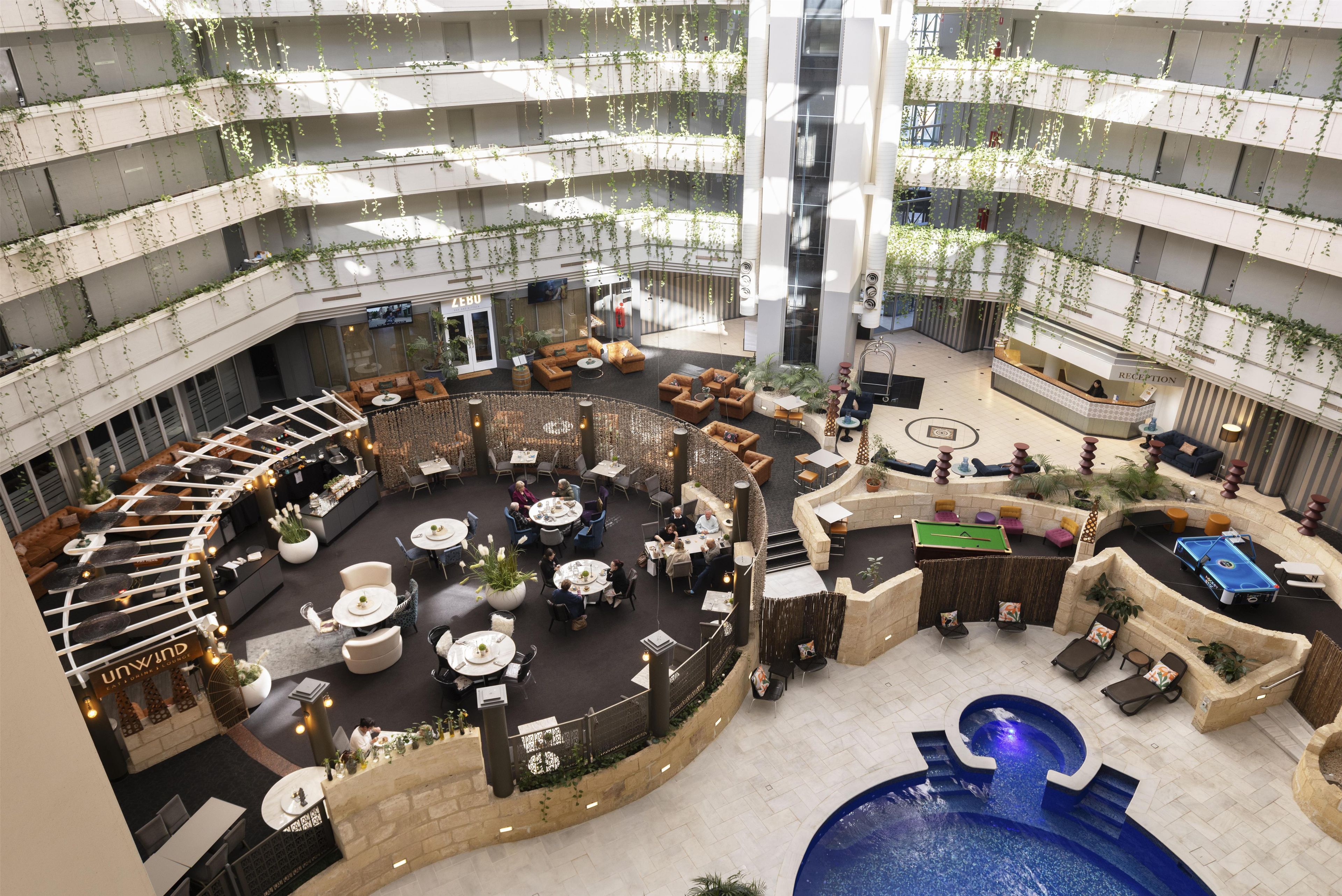 A multi-level atrium with a pool, seating areas, and a reception desk.