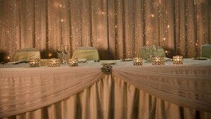 Une table dressée pour un événement formel, avec des bougies et une nappe élégamment drapée.