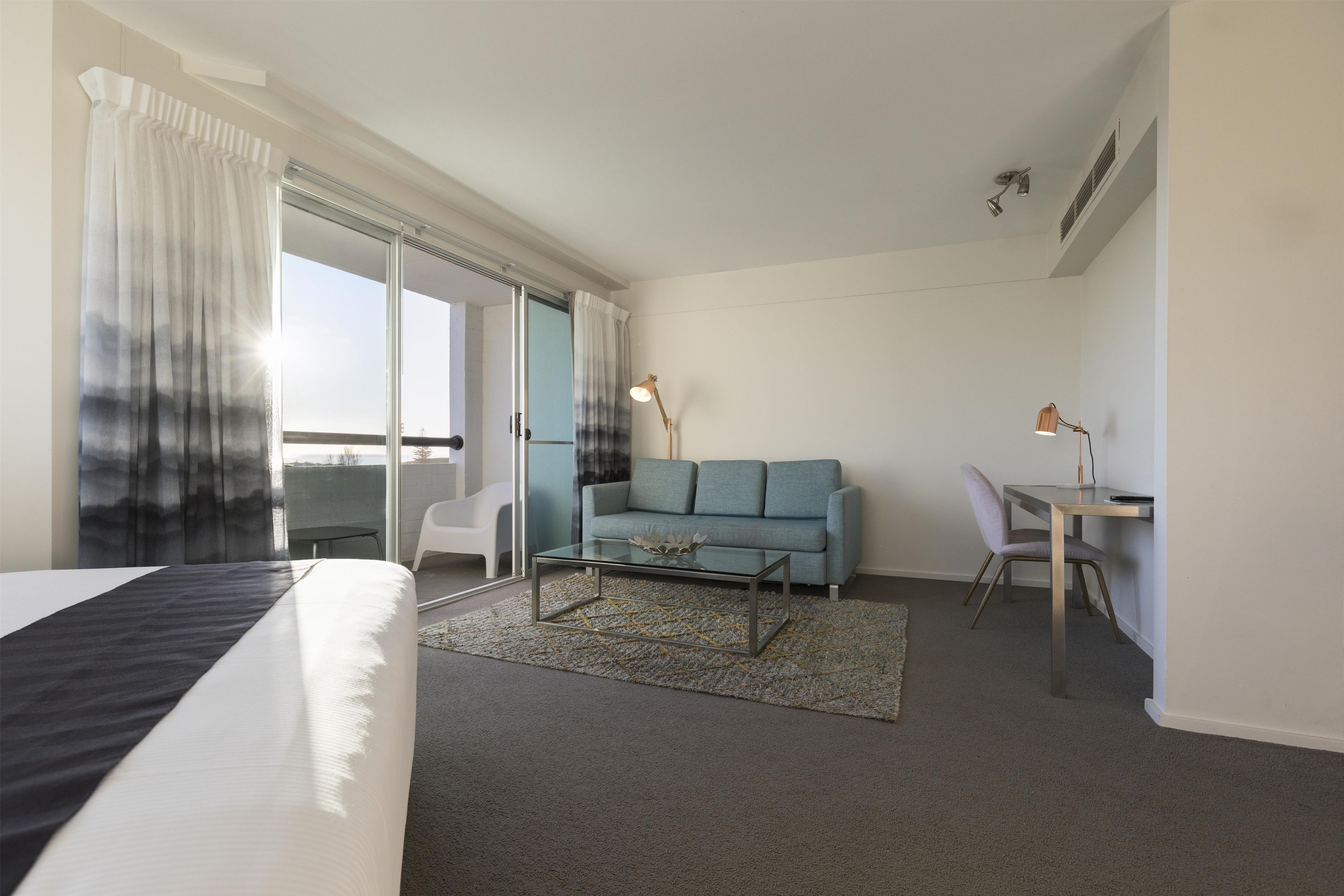 A hotel room with a bed, a sofa, a desk, and a chair.