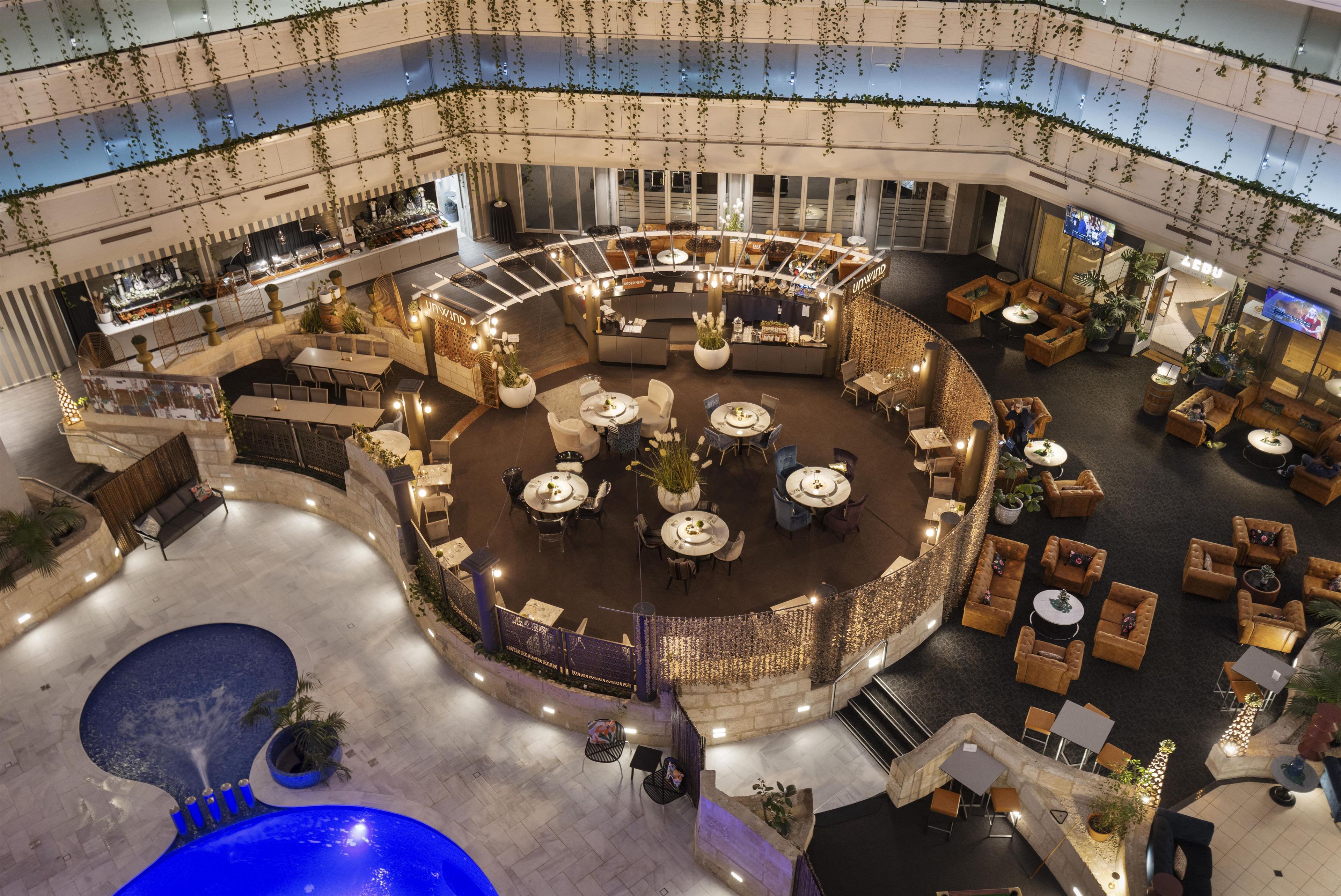 Un amplio atrio interior con varias zonas de estar, un bar central y una piscina.