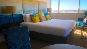 A hotel room with a large bed, two standing lamps, a view of the ocean, and a blue patterned chair. - Best Western Plus Hotel Lord Forrest (Bunbury)