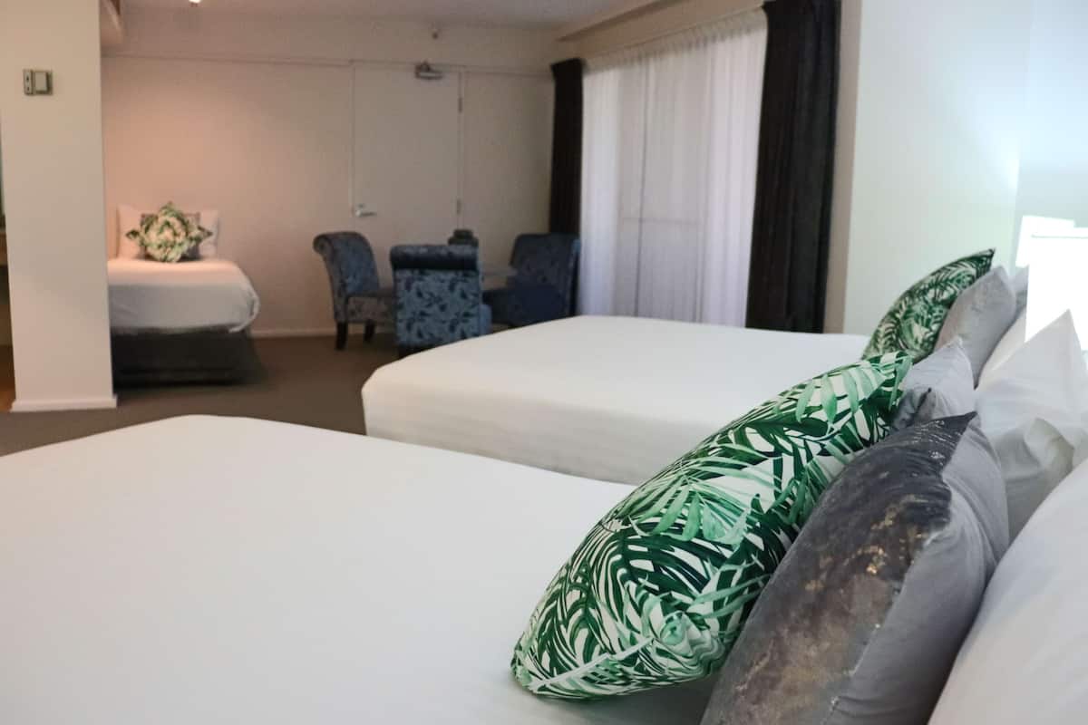 A hotel room with two beds, a desk, and a chair.