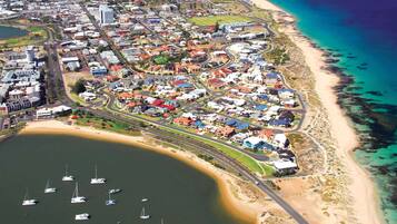 An aerial view of a coastal town with residential areas, a beach, and boats in the water.