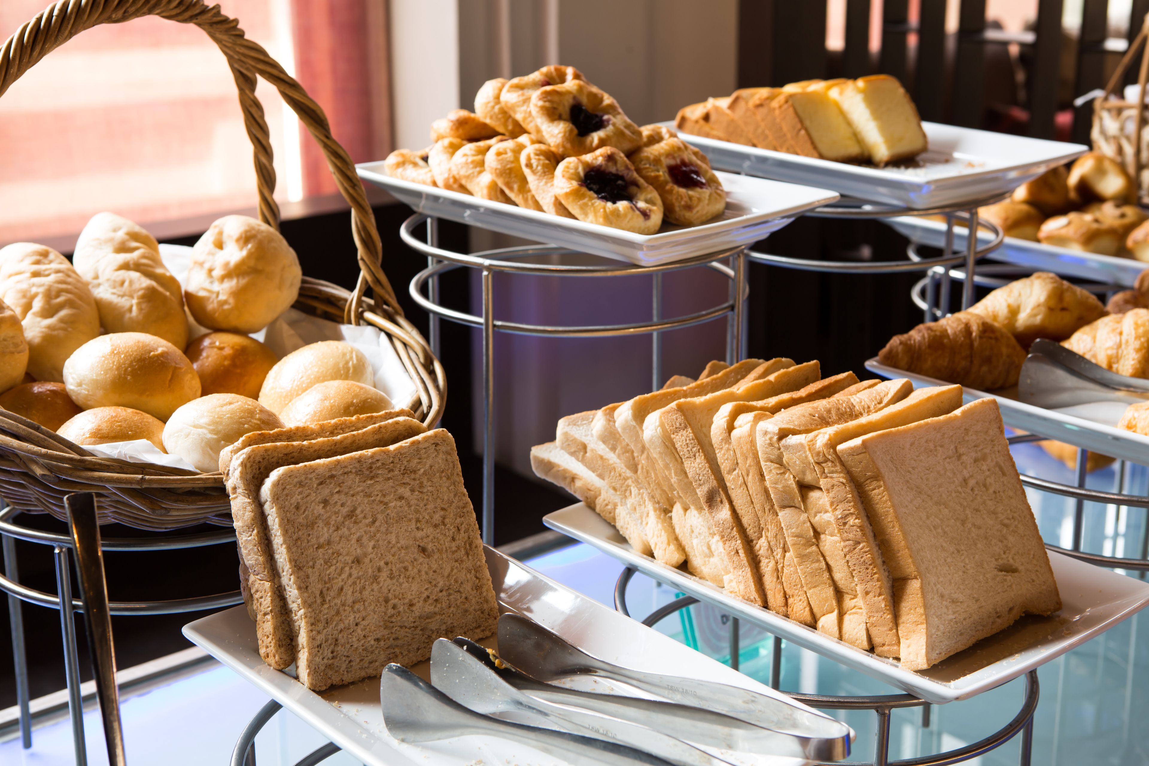 A buffet with various breads, pastries, and sandwiches.