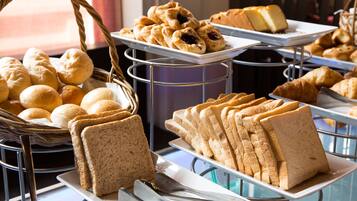 A buffet with various breads, pastries, and sandwiches.