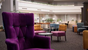 Un hall d’entrée avec un fauteuil violet, plusieurs tables et des chaises.