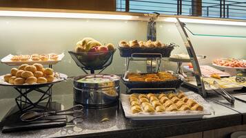 A buffet with various food items including pastries, fruits, and desserts.
