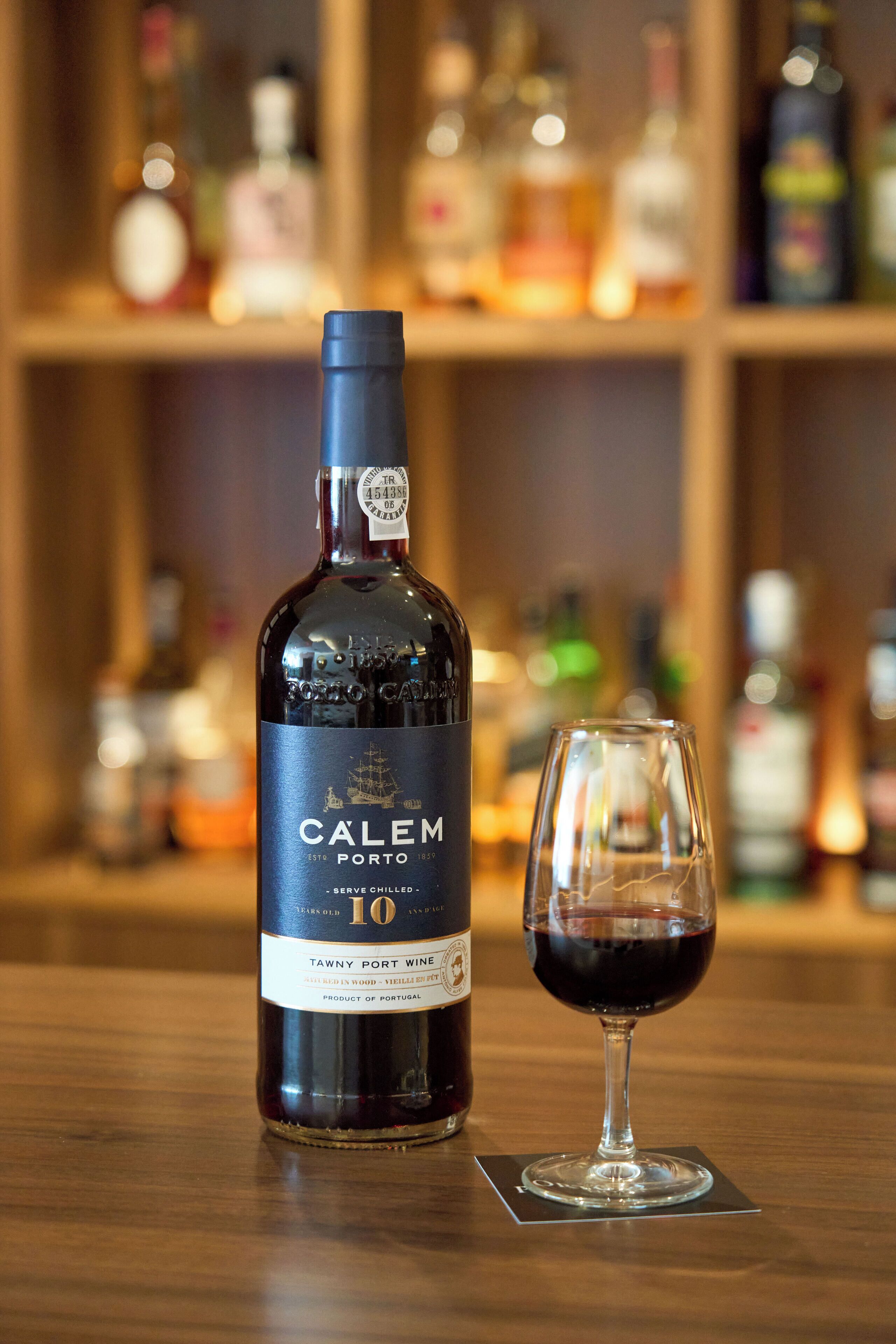A bottle of Tawny Port wine with a glass of wine beside it.