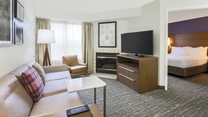 A hotel room with a sofa, armchair, TV, fireplace, and a bed. - Residence Inn by Marriott Monroe (Monroe)