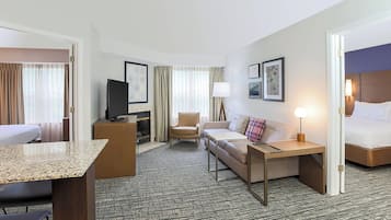 Ett hotellrum med en säng, en soffa, ett skrivbord, en tv och en stol.