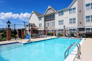 A swimming pool with a metal ladder, lounge chairs, and a brick fence. - Residence Inn by Marriott Monroe (Monroe)